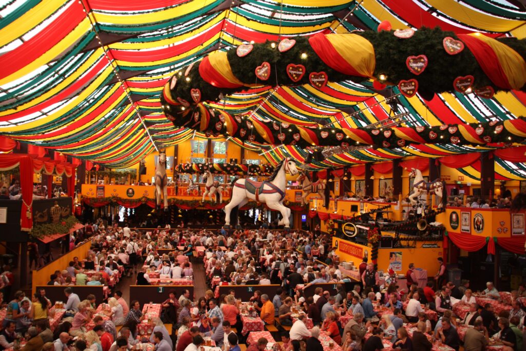 Eine große Menschenmenge im Hippodrom beim Oktoberfest, fröhlich und gesellig beim Essen und Trinken.