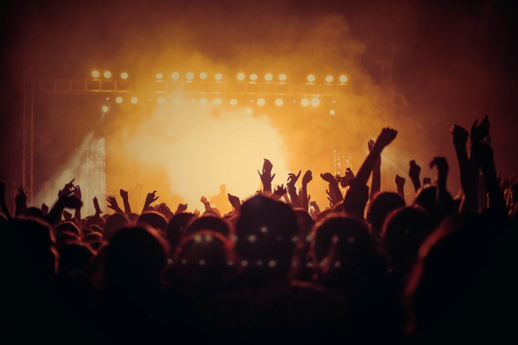 Konzertbesucher heben begeistert die Hände in die Luft und feiern die Musik in der Menge.